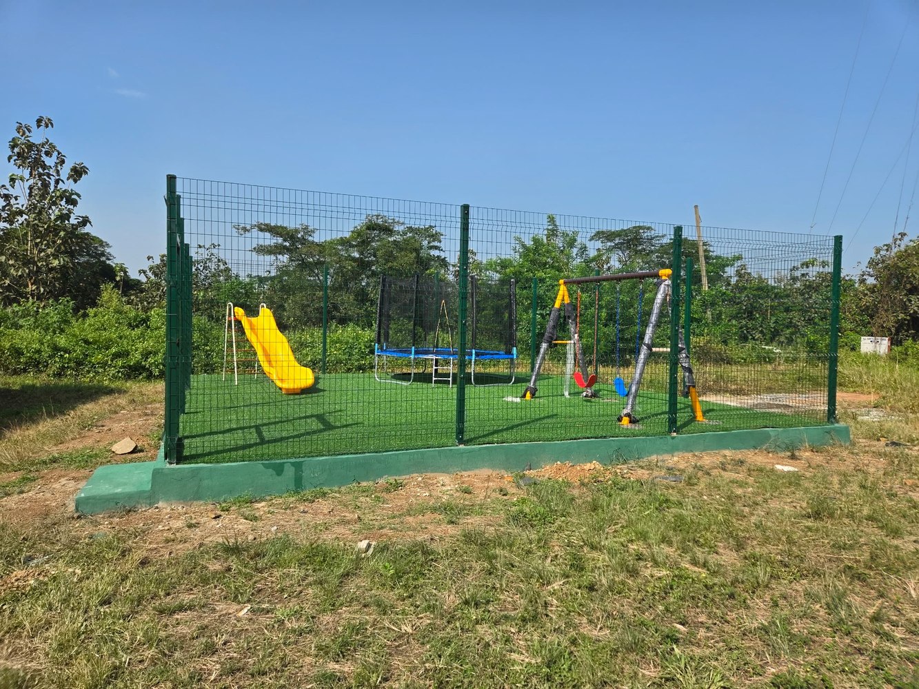 Children&rsquo;s playground &mdash; fenced, artificial grass, slide, swings, trampoline